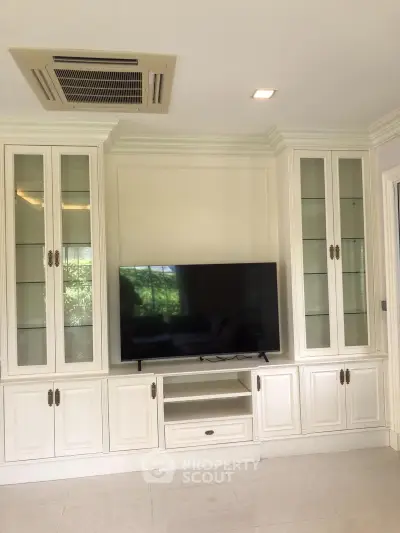 Elegant living room with built-in white cabinetry and flat-screen TV, perfect for modern home entertainment.