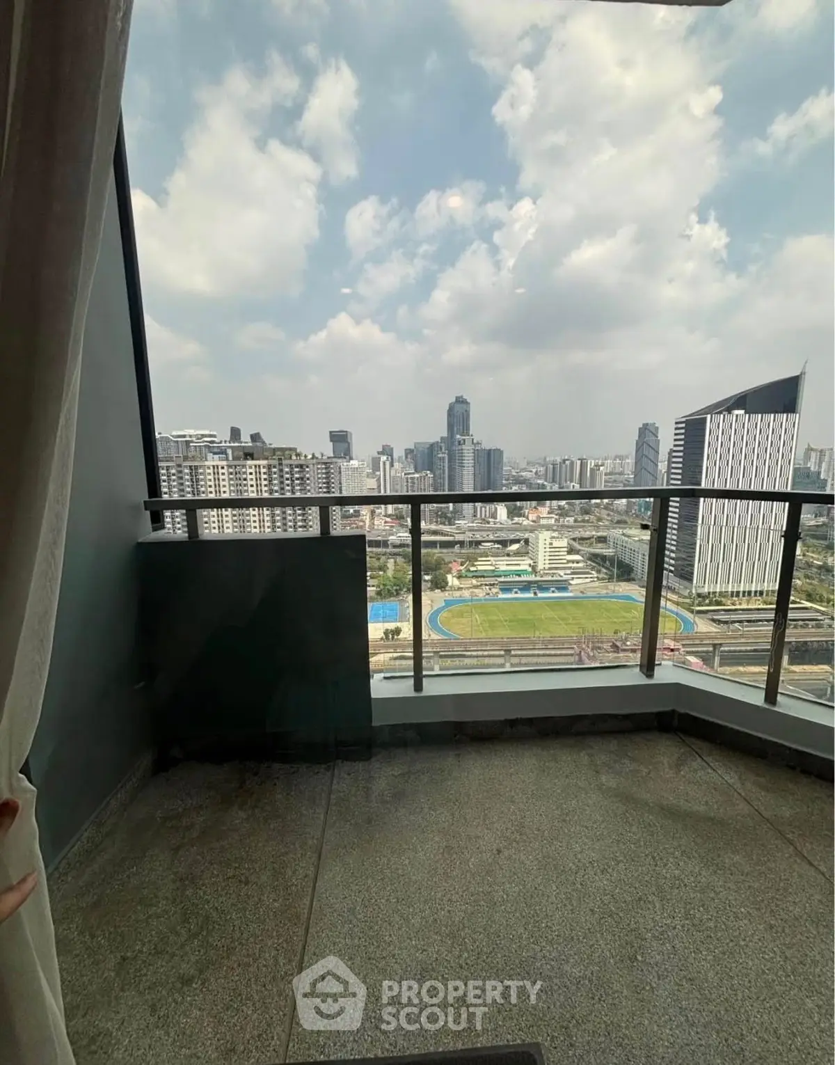 Stunning cityscape view from a high-rise balcony with glass railing.