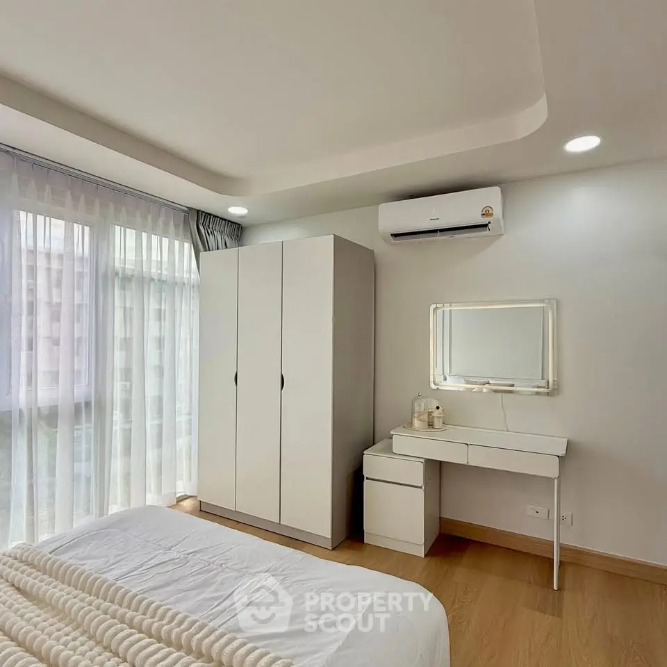 Modern bedroom with natural light, sleek furniture, and air conditioning.