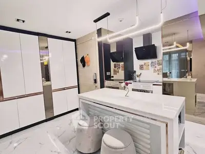 Modern kitchen with sleek white cabinets and marble island, featuring contemporary lighting and stylish decor.