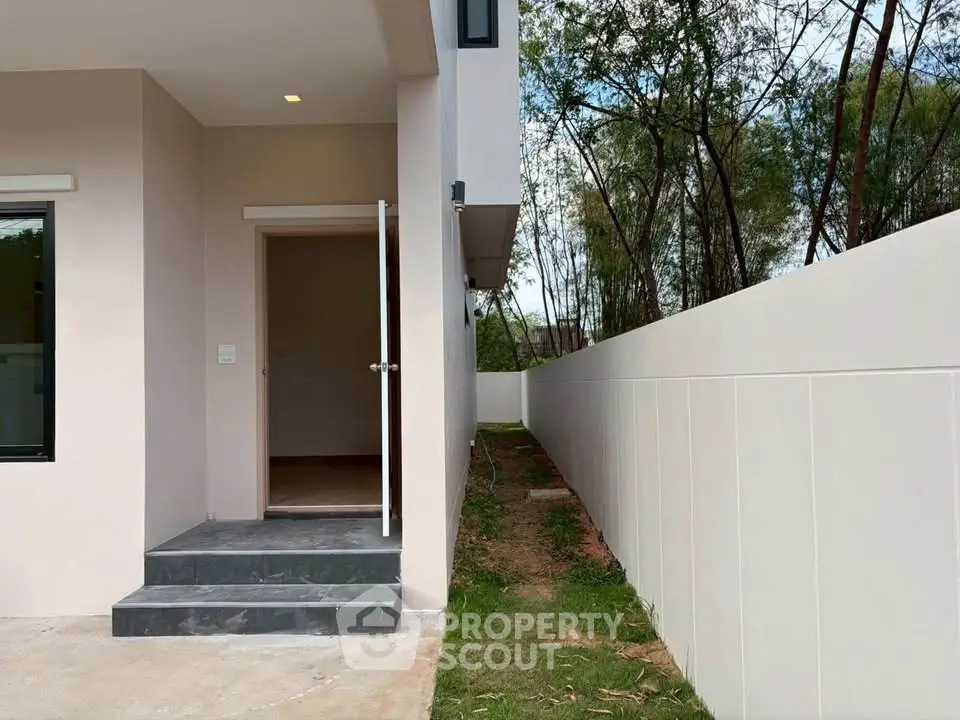 Modern exterior view of a minimalist home with clean lines and lush greenery.