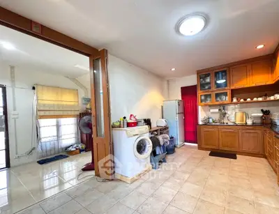 Spacious kitchen with wooden cabinets and washing machine in a cozy home setting.