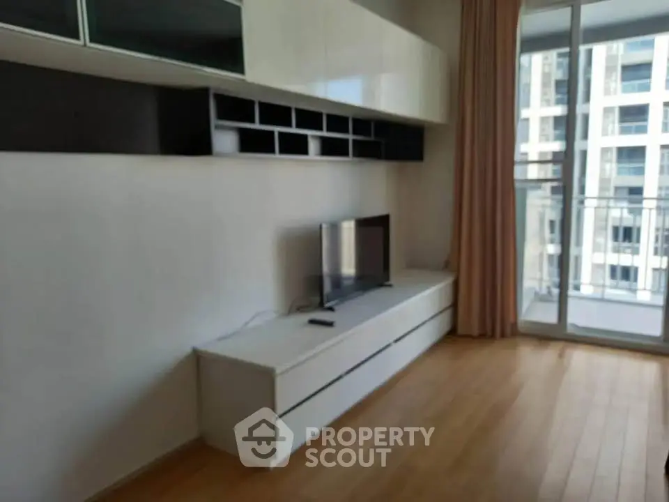 Modern living room with sleek TV unit and balcony view in urban apartment