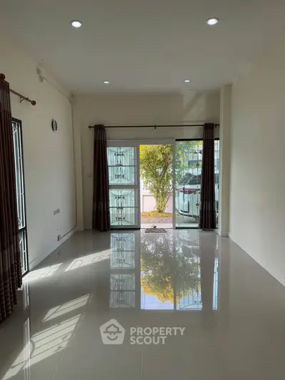 Spacious living room with glossy tiled floors and large windows for natural light