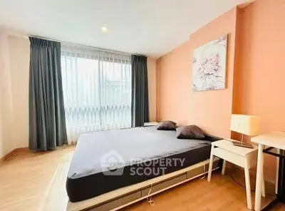 Spacious bedroom with large window and modern decor in a stylish apartment.