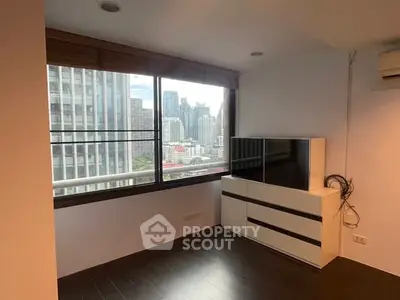 Modern apartment with large window offering stunning city view, sleek flooring, and stylish furniture.