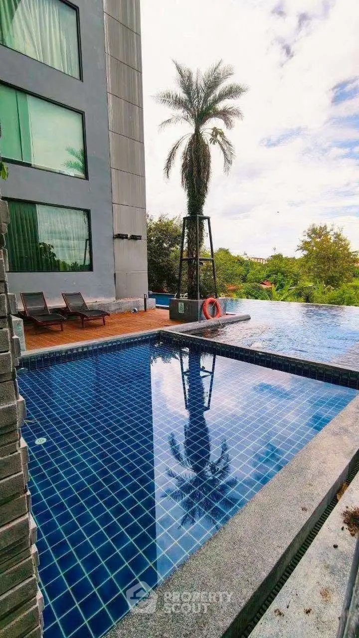 Luxurious poolside view with modern building and palm tree, perfect for relaxation and leisure.