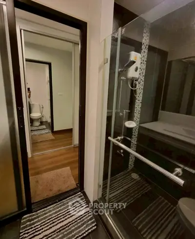 Modern bathroom with glass shower and view into adjacent toilet area