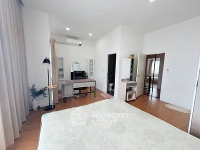 Spacious bedroom with modern decor and study area, featuring elegant furnishings and ample natural light.