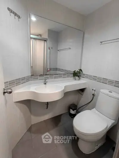 Modern bathroom with sleek fixtures and minimalist design, featuring a large mirror and contemporary sink.