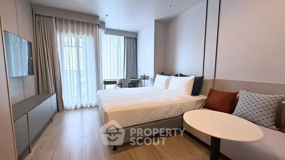 Modern bedroom with stylish decor and natural light in a high-rise apartment.