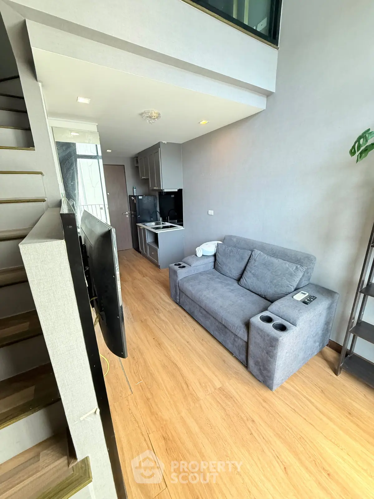 Modern loft-style living room with cozy gray sofa and sleek wooden flooring