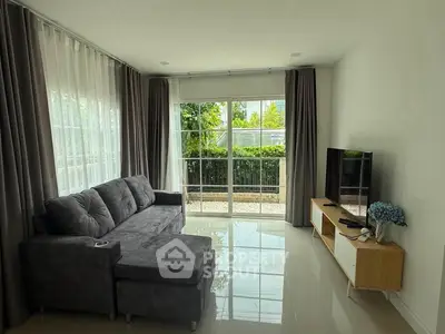 Spacious living room with modern sofa and large windows overlooking greenery, perfect for relaxation.