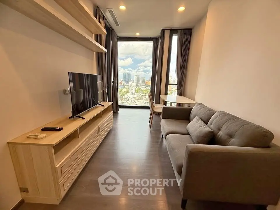 Modern living room with city view, featuring sleek furniture and large window.