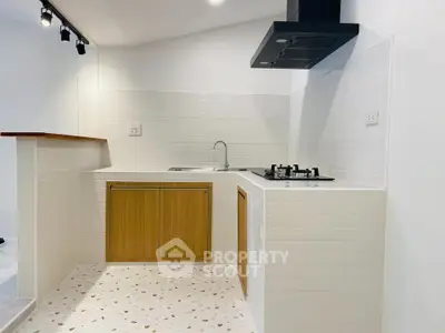 Modern kitchen with gas stove and sleek white tiles, featuring wooden cabinetry and stylish lighting.