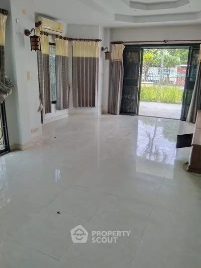 Spacious living room with large windows and garden view, perfect for family gatherings.