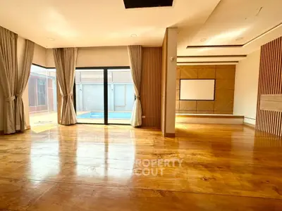 Spacious living room with wooden floors and pool view, perfect for modern living.