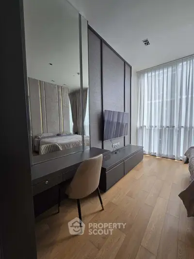 Modern bedroom with sleek design, featuring a large mirror, TV, and elegant furnishings.
