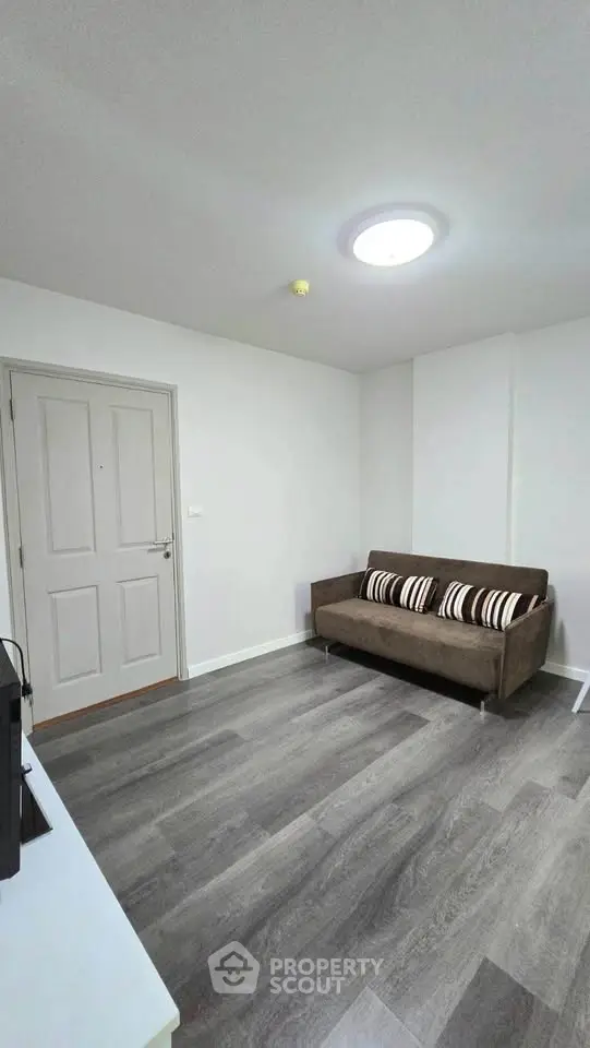 Modern living room with sleek flooring and cozy sofa in a minimalist apartment.