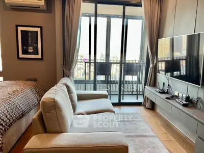 Modern living room with balcony view, featuring sleek furniture and large TV setup.