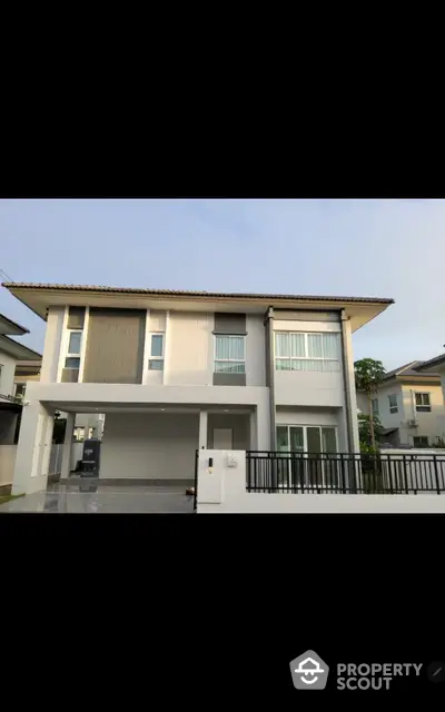 Modern two-story house with sleek design and spacious driveway in suburban neighborhood.