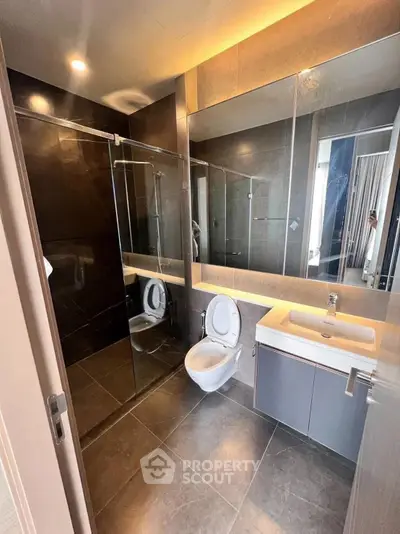 Modern bathroom with sleek design, glass shower, and wall-mounted toilet in luxury apartment.