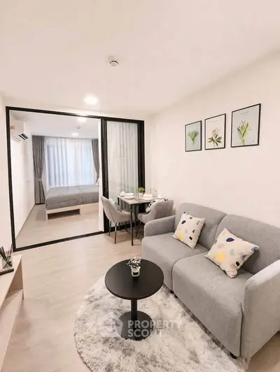 Modern open-plan living room with cozy sofa and stylish decor leading to a bright bedroom.