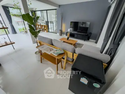 Spacious modern living room with sleek furniture and large TV, perfect for relaxation.