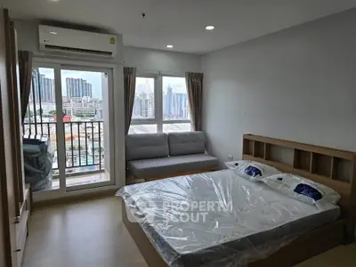 Modern bedroom with city view, featuring a cozy bed and a stylish sofa near large windows.