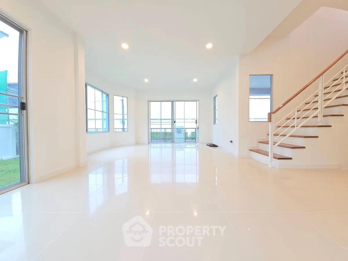 Spacious modern living room with large windows and sleek staircase