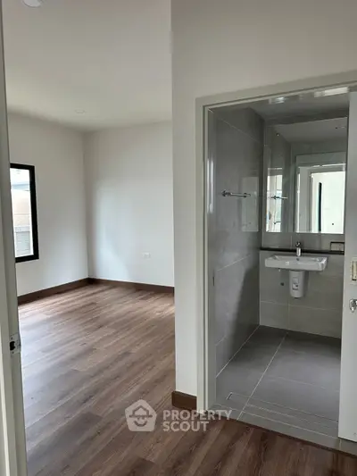 Modern apartment with sleek bathroom and spacious room, featuring elegant wood flooring.