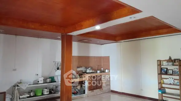 Spacious kitchen area with wooden ceiling and open shelving, perfect for modern living.