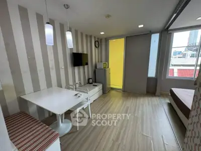 Modern studio apartment with stylish decor and city view, featuring a cozy dining area and compact kitchen.