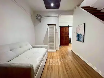 Modern interior with cozy sofa and wooden flooring, featuring a stylish staircase and wall art.