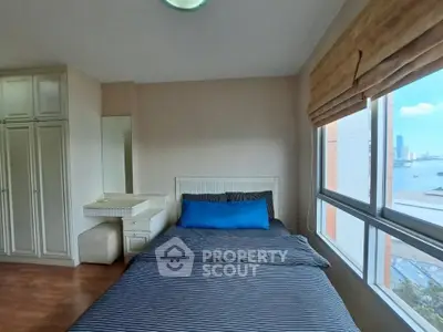 Cozy bedroom with city view, featuring a comfortable bed and ample storage space.