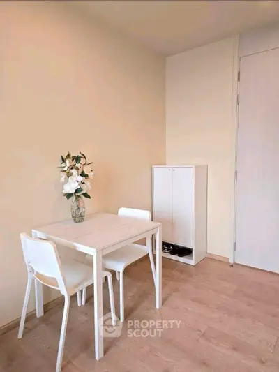 Minimalist dining area with white table and chairs, perfect for compact living spaces.