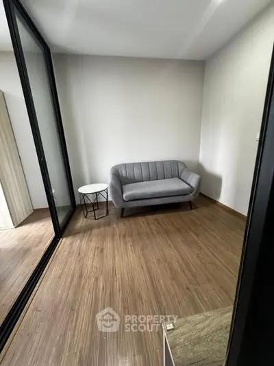 Modern minimalist living room with sleek gray sofa and wooden flooring