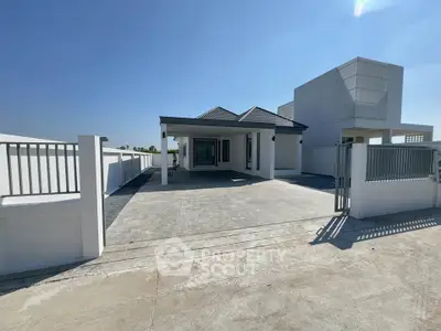 Modern single-story house with spacious driveway and sleek design under clear blue sky.
