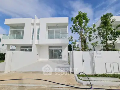 Modern white duplex with glass balconies and lush greenery