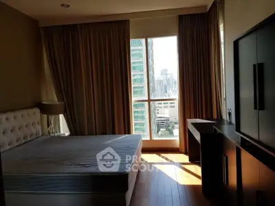 Spacious bedroom with city view and modern furnishings in high-rise apartment.