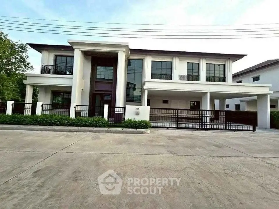 Luxurious modern two-story house with large windows and gated entrance in a serene neighborhood.