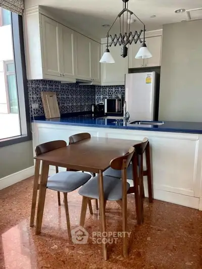 Charming kitchen with open layout and modern dining set, featuring stylish cabinetry and sleek appliances.
