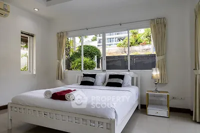 Spacious bedroom with large windows and modern decor in a serene setting.