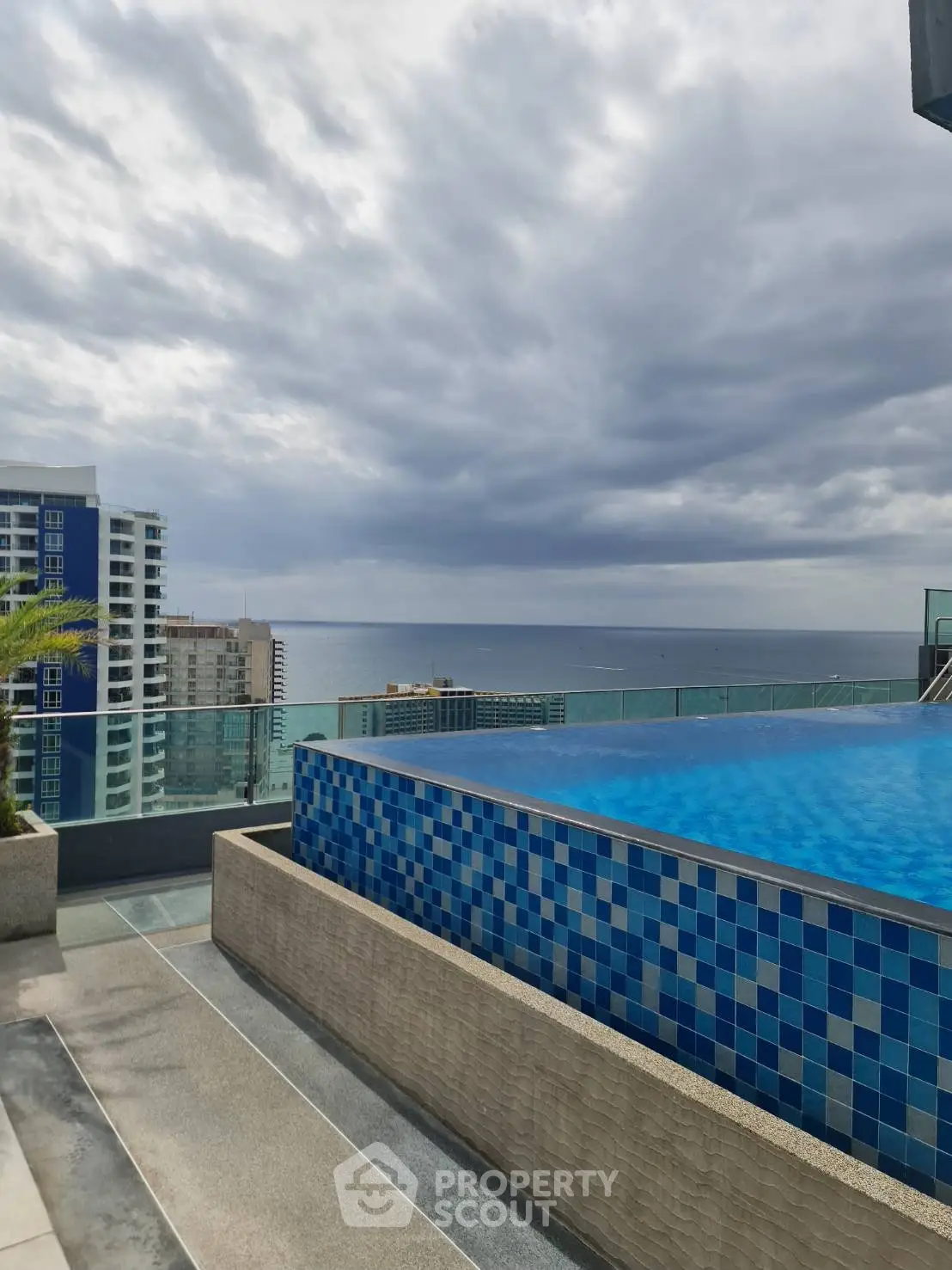 Stunning rooftop infinity pool with ocean view in luxury high-rise building.
