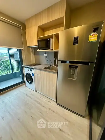 Modern kitchen with fridge, washing machine, and balcony view