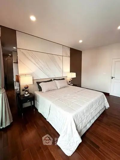 Luxurious bedroom with elegant decor and hardwood flooring, featuring a cozy bed and stylish lighting.