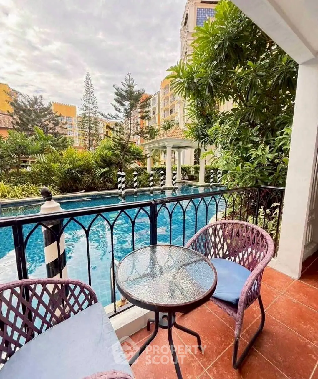 Charming balcony overlooking serene pool and lush greenery in luxury apartment complex.