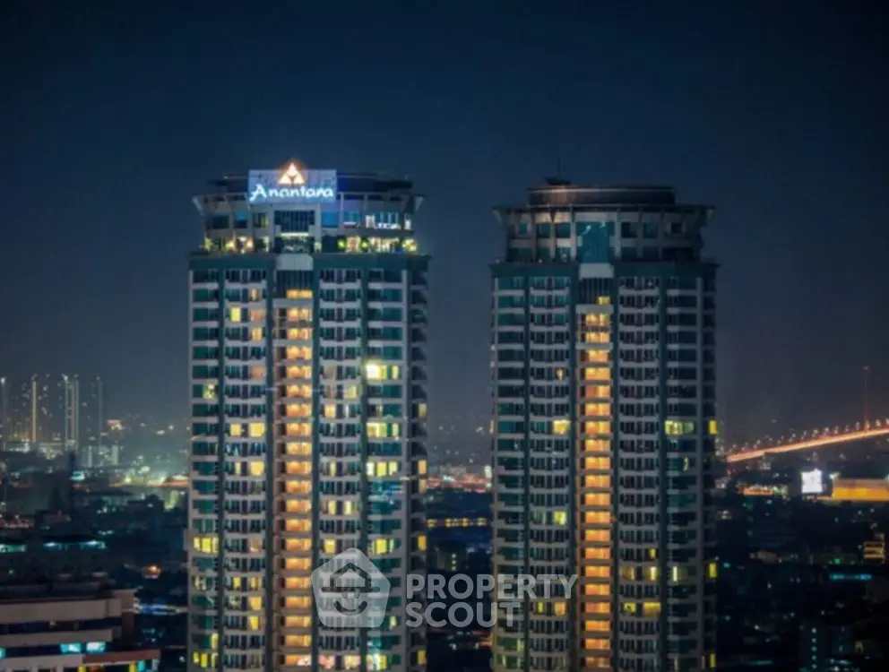 Stunning night view of twin high-rise buildings with cityscape backdrop