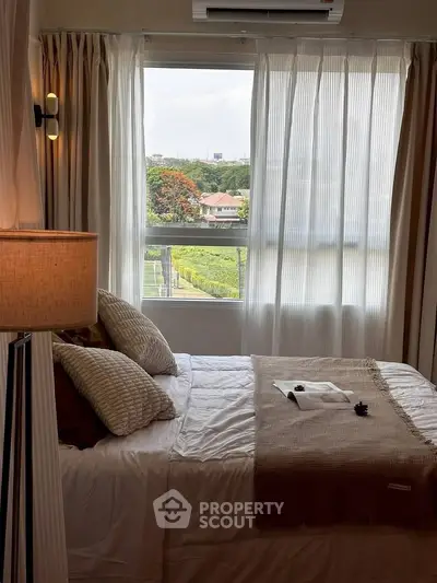 Cozy bedroom with a large window offering a scenic view, featuring elegant decor and soft lighting.