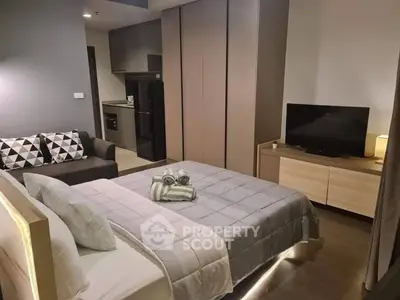 Modern studio apartment with cozy bed, stylish sofa, and sleek kitchen area, perfect for urban living.
